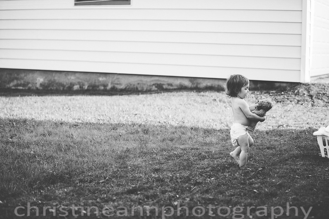 Toddler holding beloved bear wearing diaper during lifestyle session in Duluth MN.