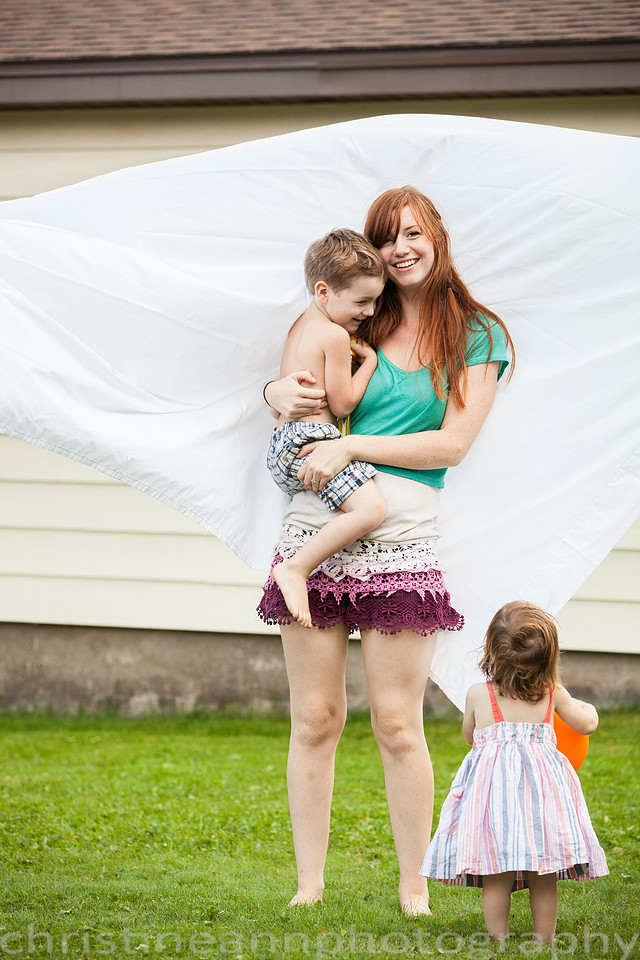 Duluth MN Lifestyle Family Session with a beloved teddy bear, apple tree, apples, sleepy kids, balloons, lawnmower, siblings, diaper, laundry, mom, dad - all outdoors in the back yard of their home.