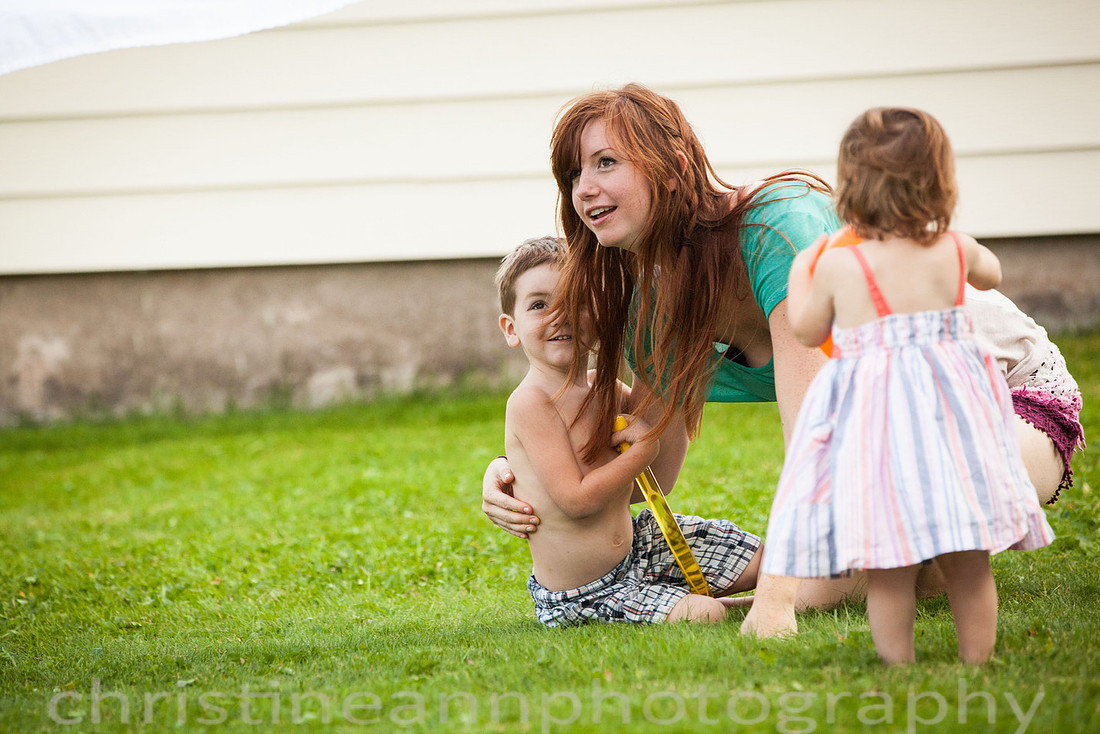 Duluth MN Lifestyle Family Session with a beloved teddy bear, apple tree, apples, sleepy kids, balloons, lawnmower, siblings, diaper, laundry, mom, dad - all outdoors in the back yard of their home.