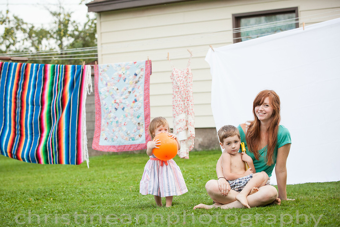 Duluth MN Lifestyle Family Session with a beloved teddy bear, apple tree, apples, sleepy kids, balloons, lawnmower, siblings, diaper, laundry, mom, dad - all outdoors in the back yard of their home.